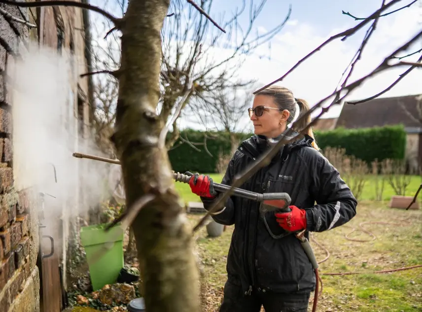 Coraline Marais, fondatrice de Brum'Azur, nettoie un mur en briques anciennes à la vapeur basse pression